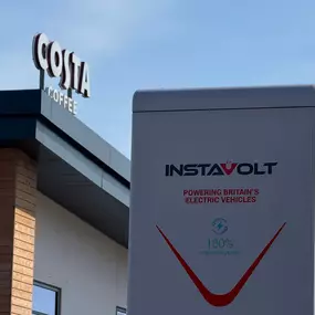 InstaVolt ultra rapid charger in front of a Costa Coffee building. The charger is branded with the tagline “Powering Britain’s Electric Vehicles” and promotes 100% renewable power, reinforcing sustainability messaging beside a well-known UK coffee chain.
