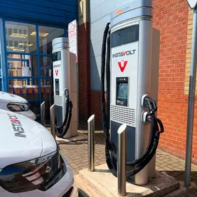 Two InstaVolt EV chargers outside Halfords in Sheldon, Birmingham, with vehicles parked in front. The chargers are easily accessible beside the store entrance, making it ideal for quick charging during shopping trips.
