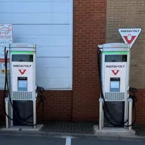 A front-on view of the InstaVolt charging station at Halfords in Sheldon, Birmingham, showing two charging units and clearly marked EV bays. Positioned for easy access within Wells Lane Retail Park.