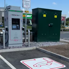 The image shows an InstaVolt rapid electric vehicle charger located at Gallagher Retail Park in Bridgwater. The charging unit is positioned in a marked bay, with clear signage and directional pavement graphics.
