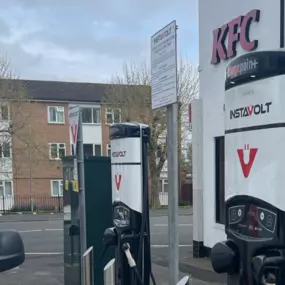 A white electric van is plugged into an InstaVolt rapid charger at Laird Street Service Station, Birkenhead, with a KFC restaurant visible in the background.