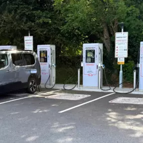A full view of four InstaVolt ultra rapid chargers with clear EV bay markings, located in a tree-lined car park next to Three Trees Farm Shop & Café.