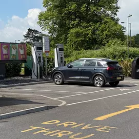 EV charging at InstaVolt bays with McDonald’s promotional signage and a leafy backdrop.