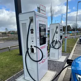 Close-up of two InstaVolt ultra rapid chargers at Leathermill Lane, Rugeley, with one charger in use and clear signage visible.