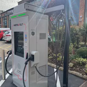 A close-up side view of an InstaVolt ultra-rapid charger at Marshall’s Yard, Gainsborough, showing cable management and a landscaped setting near nearby retail outlets.