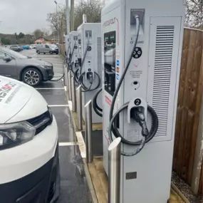 A line of InstaVolt ultra-rapid chargers at Bristol Golf Centre, each with visible instructions, charger branding, and well-organised bays. A nearby branded van reflects site activity.
