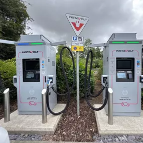 A close-up view of InstaVolt’s rapid EV charging units at OK Diner Leominster, set against lush greenery and marked with clear signage for electric vehicle recharging.