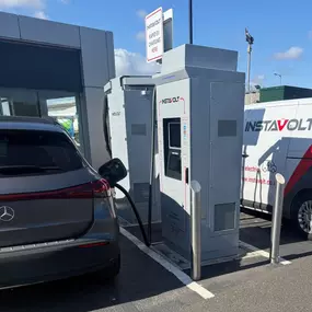 A Mercedes electric vehicle charges at InstaVolt’s ultra rapid EV chargers located in McDonald's Middlesbrough, next to a modern building with clear branding and signage.