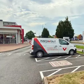 An InstaVolt-branded electric van charging at ultra rapid EV charging stations located in the car park of KFC Sheldon on Coventry Road, Birmingham. The chargers are clearly marked with a “Rapid Charge Here” sign, and the KFC building is visible in the background.