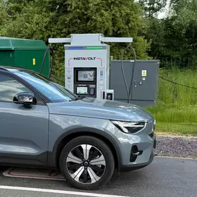 This detailed view captures a grey EV actively charging at InstaVolt’s facility near Cobbs Farm Shop. The unit’s user interface and contactless payment panel are visible, showcasing ease of use in a rural yet well-equipped setting.