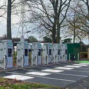A line of InstaVolt ultra-rapid chargers at Corley Northbound Services, set in a leafy area with marked EV bays ready for use.