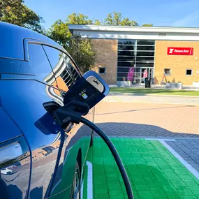 A BMW charges at an InstaVolt unit, parked in a green bay with smart landscaping.
