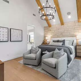 Tranquil primary bedroom retreat with wood flooring, feature wall and vaulted ceiling