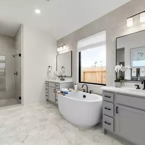 Spa-inspired primary bathroom with dual vanities, freestanding soaking tub and oversized shower