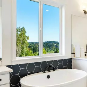 Luxe primary bathroom with free-standing tub and separate vanities