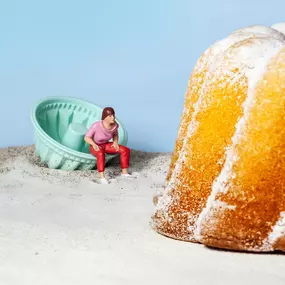 SW Kommunikation Surreale Darstellung mit einer kleinen Figur vor einer Backform und Kuchen, fantasievoll und kreativ inszeniert