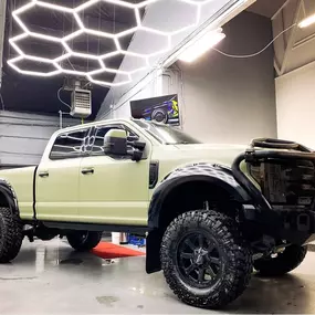 Custom-wrapped Ford Super Duty pickup at VersionEX Auto in Eugene, OR, finished in a sleek matte color with rugged off-road upgrades. The image highlights VersionEX’s expertise in vehicle wraps, customization, and high-end detailing under their state-of-the-art shop lighting.