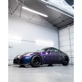 Nissan 350Z finished in a striking custom color-shift wrap at VersionEX Auto in Eugene, OR. The glossy purple-blue finish highlights the shop’s precision in vehicle wraps, paint protection, and performance styling inside their professional detailing bay.