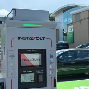 Close-up of an InstaVolt EV charger with user screen and payment terminal, located near Nuffield Health Fitness & Wellbeing Centre.