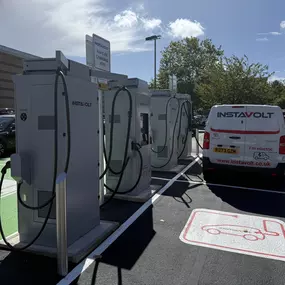 InstaVolt charging units with an EV van connected, set in a clean, accessible parking area surrounded by trees.