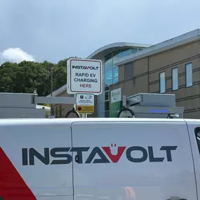 InstaVolt ultra-rapid charging signage and branded van positioned outside a Nuffield Health centre in a busy car park.