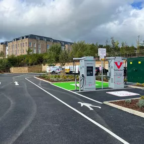 Two InstaVolt ultra-rapid EV chargers in a landscaped car park, with residential buildings in the background at Station Road, Buxton.
