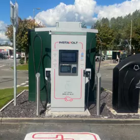 Frontal view of an InstaVolt charger at Marus Bridge Retail Park in Wigan, positioned between McDonald’s and The Food Warehouse, offering easy access to retail and dining for EV drivers.