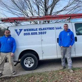 Owners of Wehrle Electric LLC standing in front of company service van with logo and phone number, licensed electricians in Covington KY serving a 40-mile radius.