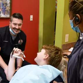 A dentist and dental assistant talk to a young patient.