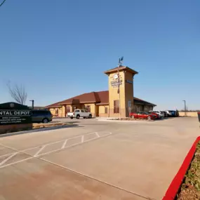 Exterior view of Dental Depot's dentist office on Mustang Rd. with a red roof, yellow exterior, and model train.