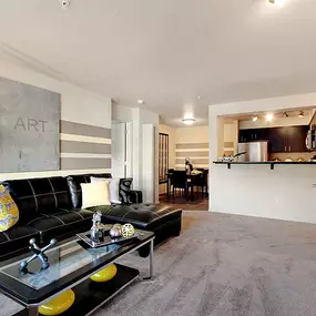 A modern living room with a black couch and a fireplace.
