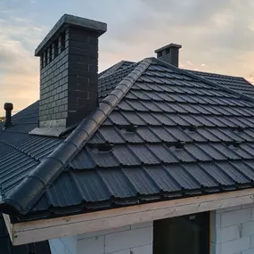 Finished roof replacement with dark composite tiles and new chimney flashing. LS Contracting craftsmanship built for beauty and performance.