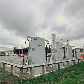 A rear-facing shot of InstaVolt chargers installed at McDonald’s Leek location. The chargers face green parking bays, while the McDonald’s restaurant and parked cars can be seen in the background under a cloudy sky.