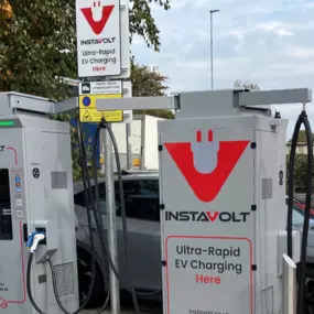 Two InstaVolt ultra-rapid chargers next to the Tower Retail Park sign featuring Matalan and Hobbycraft, with an electric vehicle plugged in.