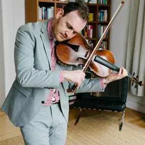 dunkelgoldmusik | Hochzeits- und Veranstaltungsmusik Musiker im eleganten Anzug spielt Viola für emotionale Hochzeitsmomente im stilvollen Ambiente. Foto von Julius Kürschner.