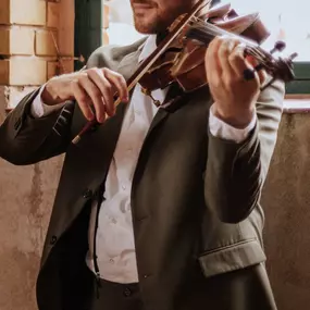 dunkelgoldmusik | Hochzeits- und Veranstaltungsmusik Künstlerische Aufnahme eines Violinisten bei Hochzeitsmusik im Vintage-Ambiente. Foto von Madeleine Rothkugel.