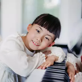 Elite Musik Ein junges Mädchen posiert liebevoll am Klavier und vermittelt eine warme, musikalische Atmosphäre.