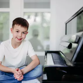 Elite Musik Ein Junge neben einem Klavier, ideal für Themen wie Musikunterricht, Motivation und kreative Freizeitgestaltung.