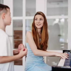 Elite Musik Eine Lehrkraft vermittelt musikalisches Wissen und begleitet einen Jungen während des Unterrichts.