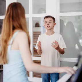 Elite Musik Ein Schüler entwickelt seine gesanglichen Fähigkeiten, unterstützt durch Klavierbegleitung.