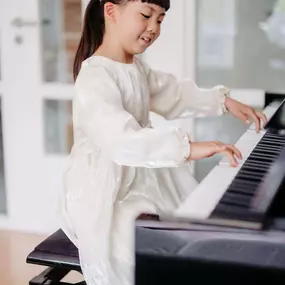 Elite Musik Ein Kind, das mit Freude am Klavier sitzt – geeignet für Inhalte rund um musikalische Entwicklung.