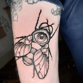 Schmierfink & Robird außergewöhnliches tattoo einer fliege mit integriertem auge im körper, surrealistischer stil mit dotwork und realistischen details, kunstvoll gestochen auf oberarm