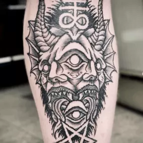 Schmierfink & Robird komplexes blackwork tattoo eines dämonischen gesichts mit symbolen und pentagramm, detaillierte linienführung und kraftvolle tätowiertechnik