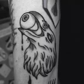 Schmierfink & Robird dunkles tattoo eines vogelkopfes mit surrealem auge im schnabel, kräftige linien und pointillismus schattierung für intensiven kontrast