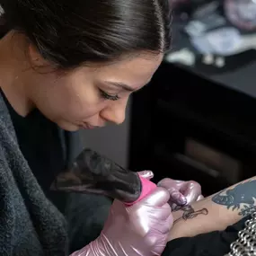 Schmierfink & Robird professionelle tätowiererin konzentriert beim stechen eines fine line tattoos, präzise arbeit und saubere hygiene in modernem studio
