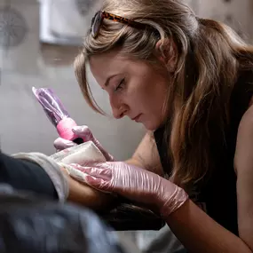 Schmierfink & Robird künstlerische tätowiererin vertieft in die umsetzung eines individuellen tattoo designs, kreative handarbeit mit erfahrung und ruhe