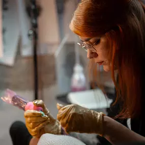 Schmierfink & Robird konzentrierte tätowiererin mit roten haaren erstellt detailreiches tattoo design, kunstvolle linien und kreative umsetzung