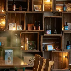 Der gemütliche Ausschankraum der Wildwuchs Brauerei in Hamburg überzeugt mit rustikalem Charme und liebevollen Details. Warme Lichtquellen, alte Holzkisten und handgebraute Biere schaffen eine authentische Atmosphäre, die zum Verweilen einlädt.