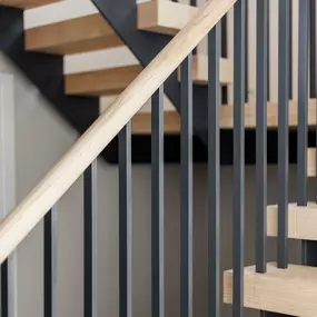 Modern staircase with wooden steps and black metal railing in Poole home.