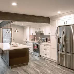 An electrician wearing gloves uses a multimeter to check the voltage on yellow-sleeved wiring within a large industrial electrical control panel.